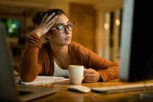 Femme fatiguée devant son ordinateur se demandant comment arrêter de procrastiner