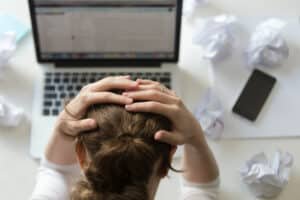 Personne en situation de stress devant son ordinateur, illustrant les premiers signes de Burn-out au travail.