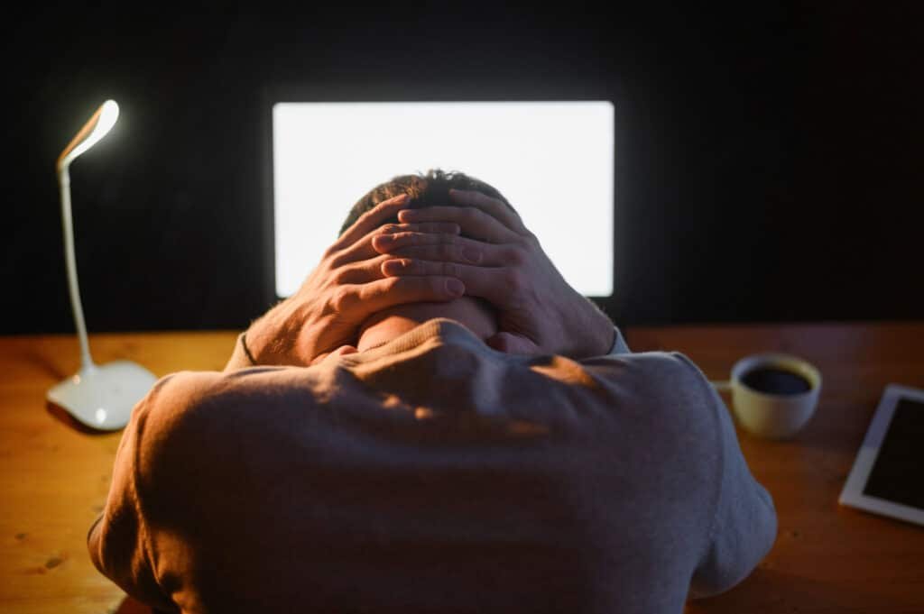 Personne épuisée devant son ordinateur tard le soir, symbole d’un Burn-out lié au stress chronique.